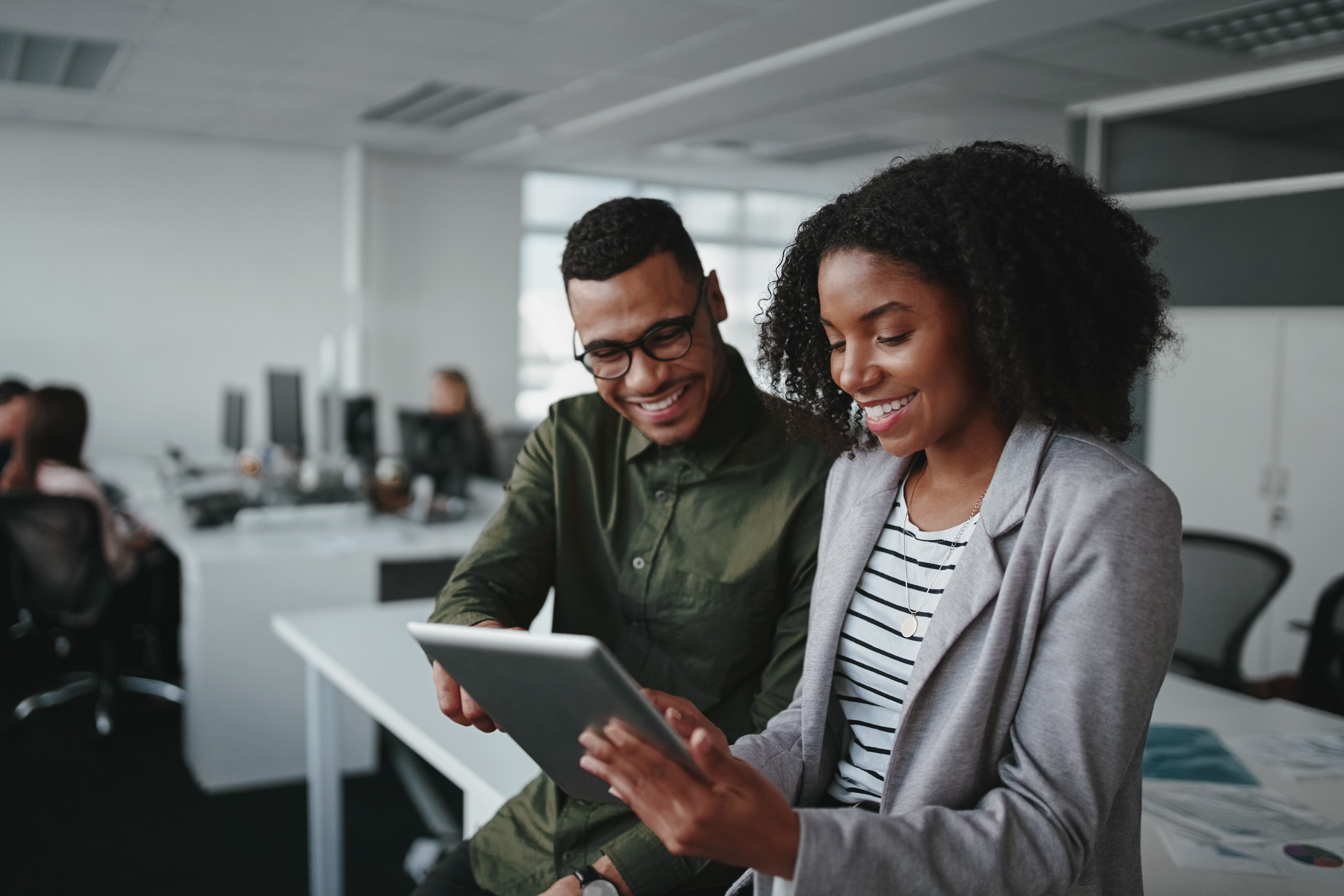 A man and a woman smile at a tablet